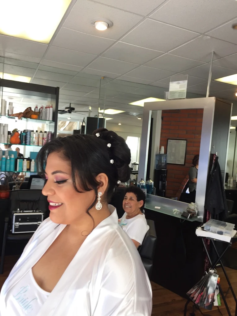 Woman with upswept black hair and pearl pins smiling in a salon, wearing white robe