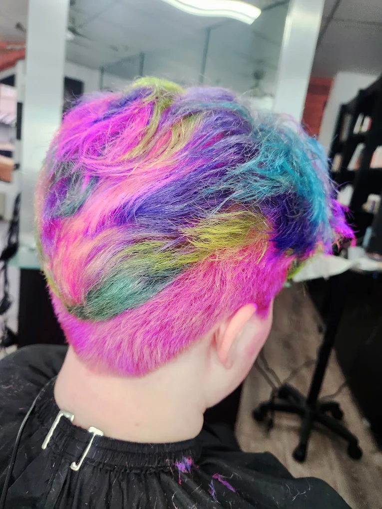 Vibrant multicolored hair featuring pink, purple, blue, and yellow dye in a salon setting