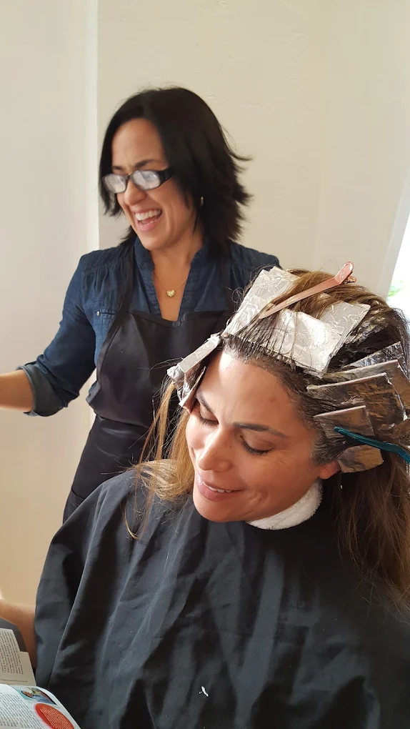 Hair stylist applying color treatment to client's hair in salon