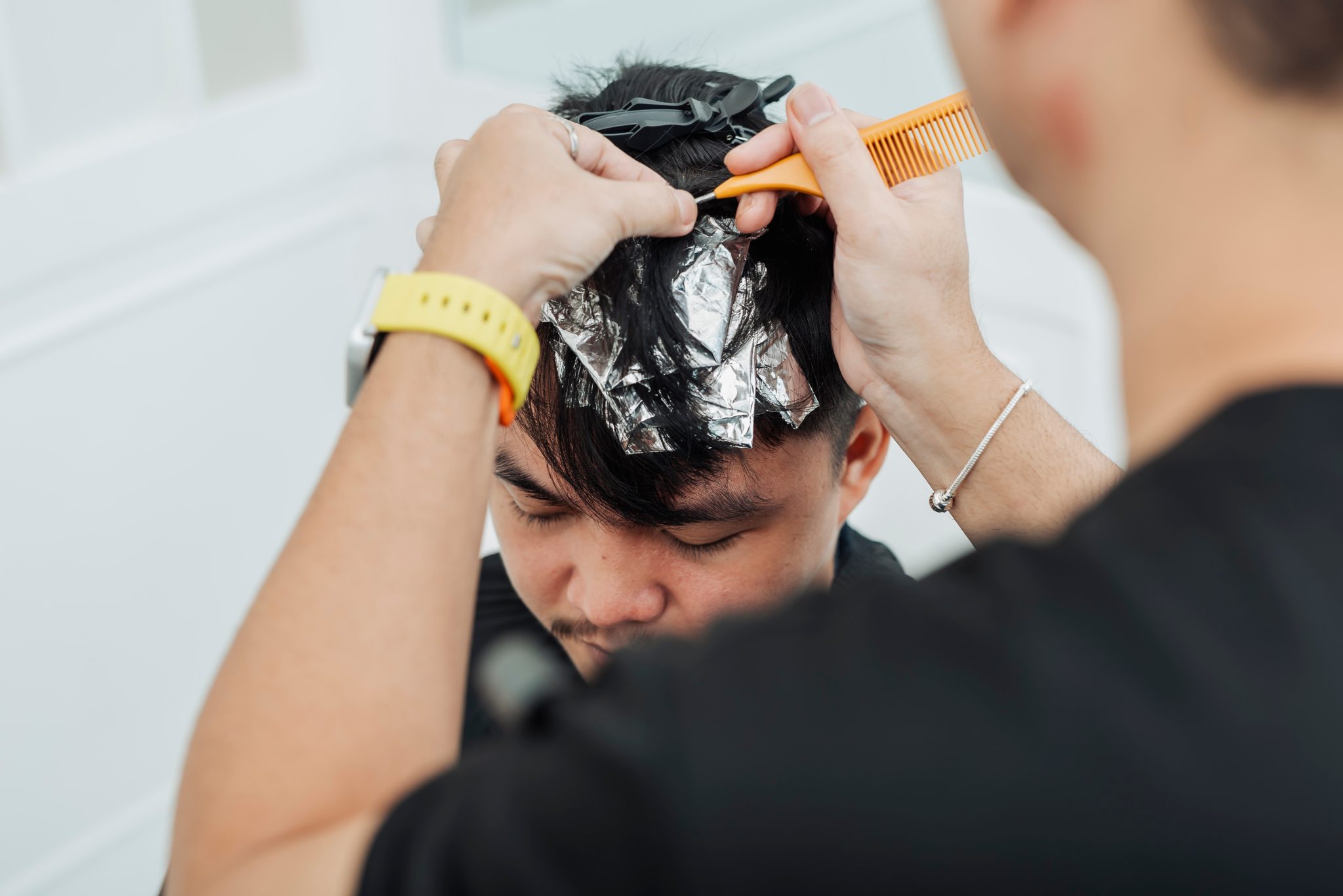 Barber applying hair dye with brush and foil to client's hair