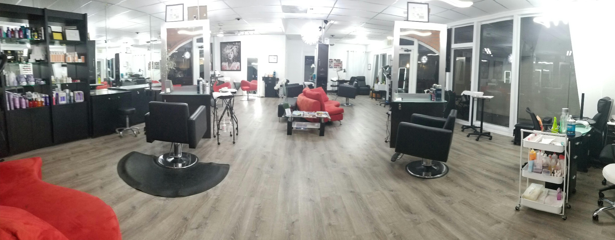 Modern salon interior with black styling chairs, red seating, mirrors, and product displays